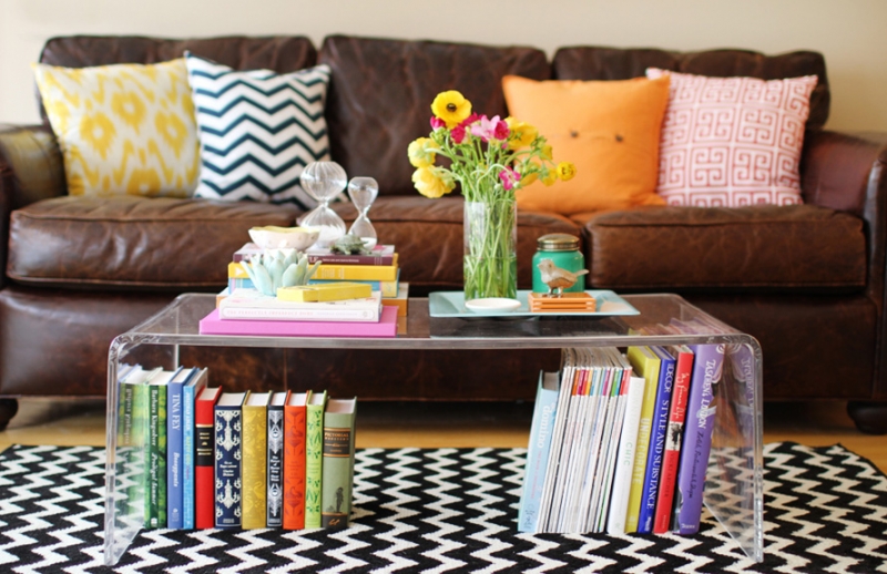mesa de centro de acri╠ülico decorada com livros flores e objetos decorativos pessoais
