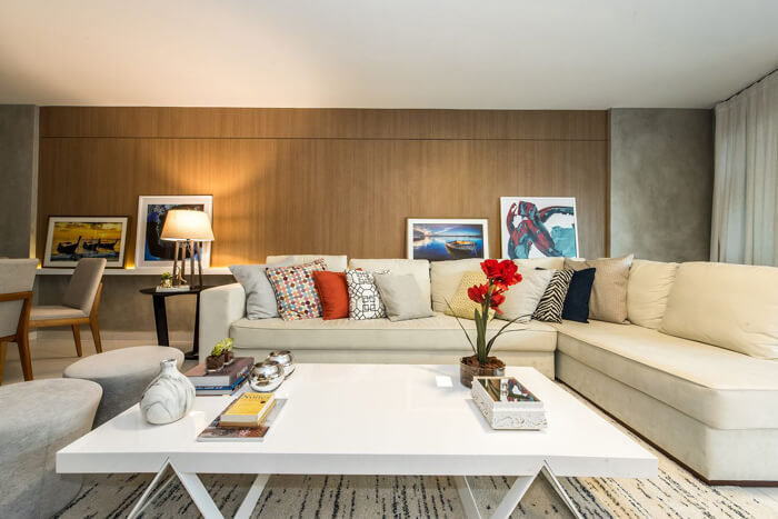 imagem de uma sala moderna e clara, com um sofá de canto com várias almofadas 
