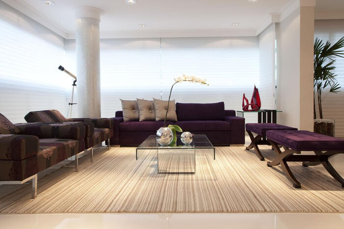 imagem de uma sala moderna com sofá e bancos roxos. 