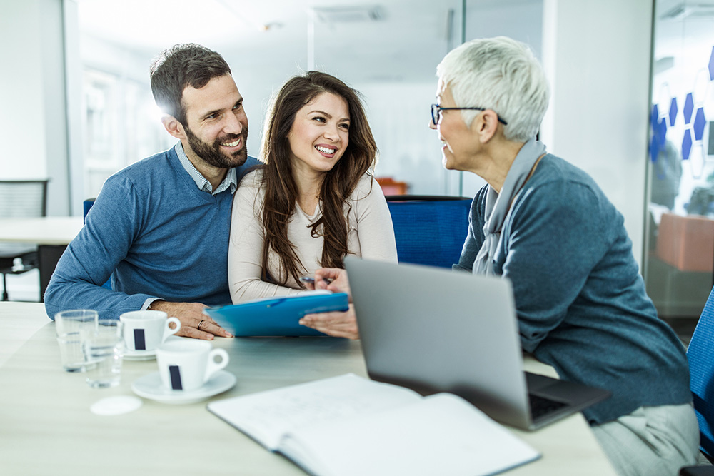 imagem de um casal conversando com uma corretora de imoveis 
