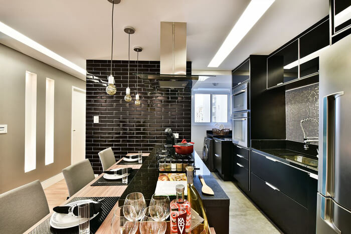 cozinha preta moderna, com uma parede de tijolo à vista pintada de preto