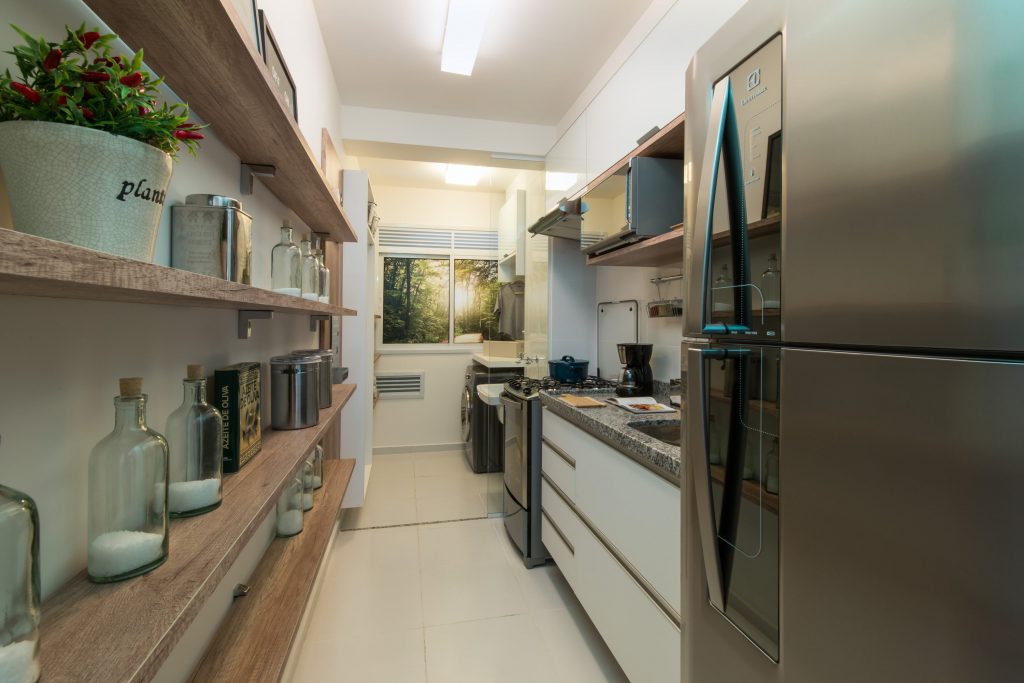 imagem de uma cozinha pequena, porém bem dividida, com prateleiras que armazenam potes e decorações 