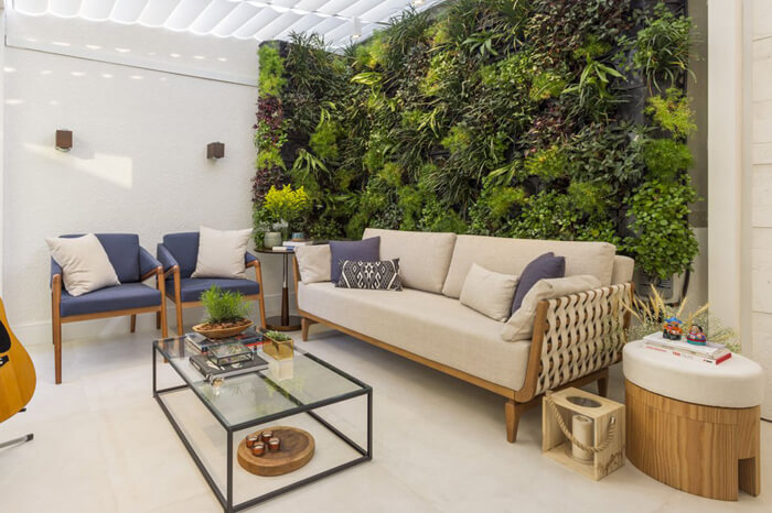 living com sofá, poltronas, mesa de centro e parede com plantas horizontais.