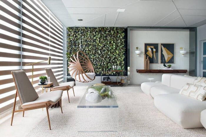 imagem de uma sala de estar com sofá, poltrona e uma parede verde de plantas