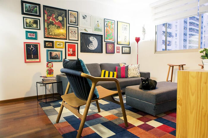 imagem de uma sala de estar com sofa, poltrona e quadros divertidos na parede