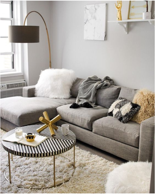 Sala moderna com sofá, uma luminária e uma mesa no centro.