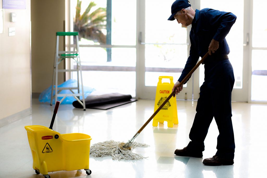 Zelador limpando o chão.