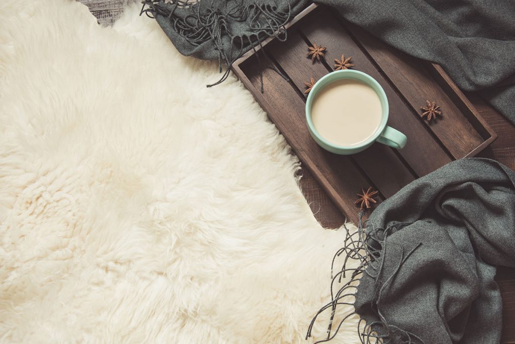 Imagem mostra um tapete fofinho de pelo e uma xícara de café