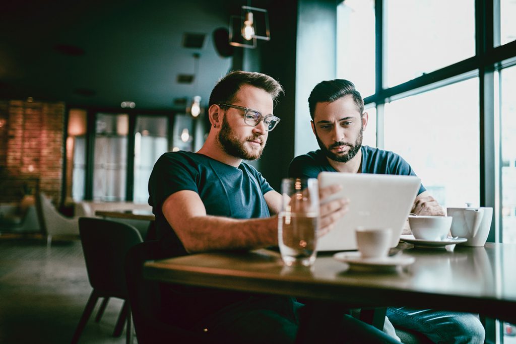 Dois homens sentados em frente ao notebook
