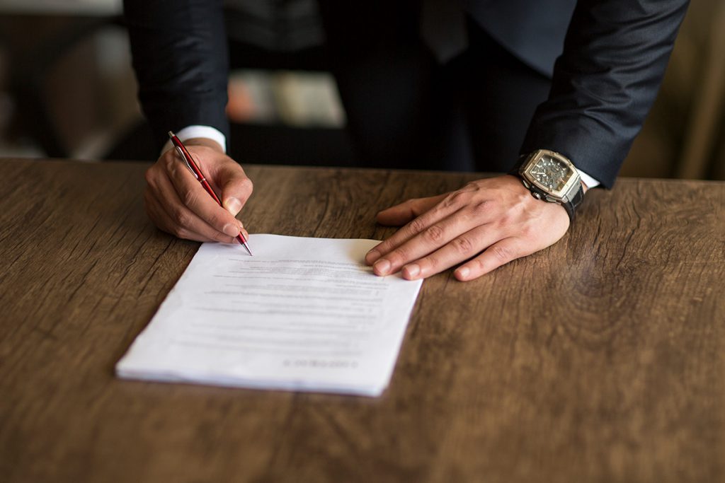 Imagem mostra homem assinando documentos 