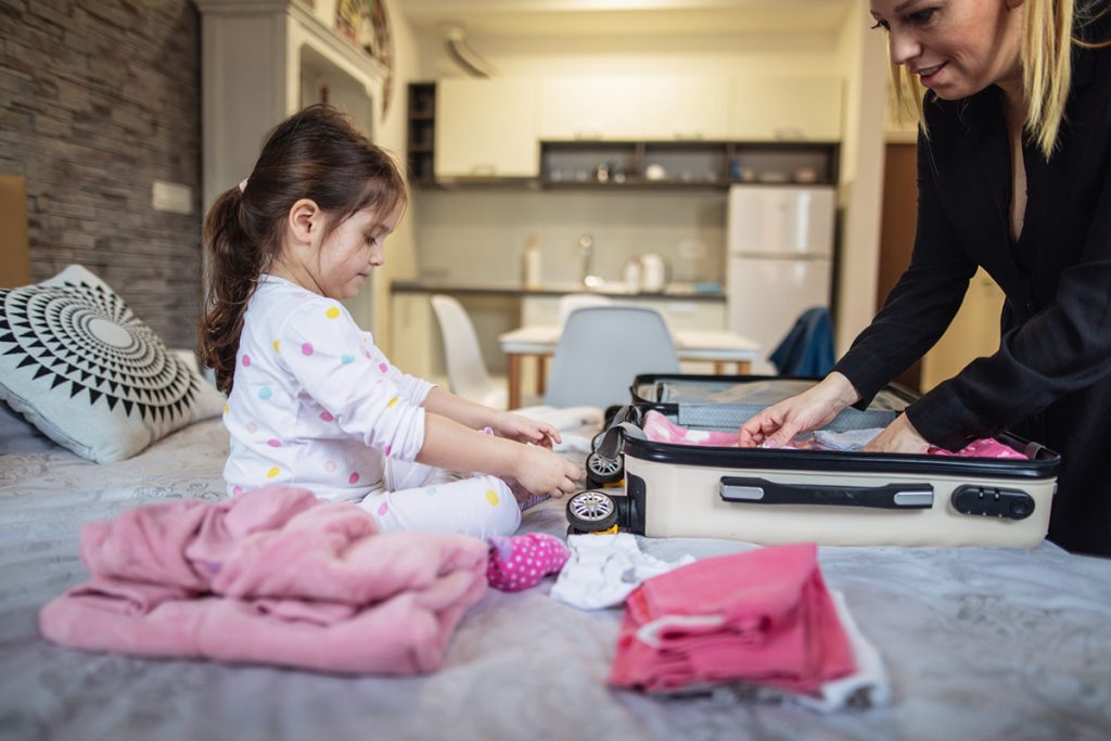 Menina arrumando sua mala com a sua mãe 